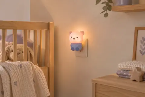 Veilleuse électrique en forme d’ours, rose et bleue, branchée dans une chambre de bébé.