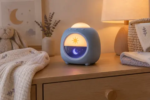 Réveil éducatif bleu avec veilleuse posé sur une commode en bois clair dans une chambre de bébé.